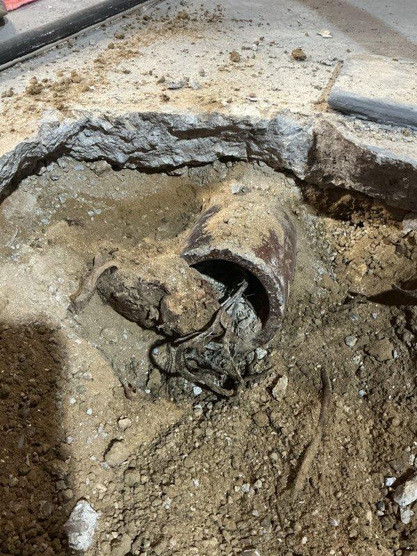 Performed camera inspection and sold repair estimate for floor break issue. Investigation revealed severely corroded metal pipe requiring replacement, with excavation exposing significant deterioration and oxidation. Documented damaged concrete/mortar surface with new PVC pipe installation including metal fittings and connectors.