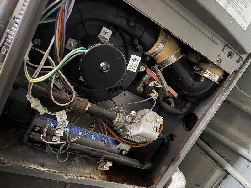 Diagnosed excessive noise from 16-year-old furnace located in utility room. Inspection revealed worn blower motor (FASCO model) with failing bearings causing the reported banging noise. Replaced blower motor assembly, reconnected wiring harness (green, yellow, blue, white, and black wires), and tested system operation. Unit now functioning properly with normal noise levels.