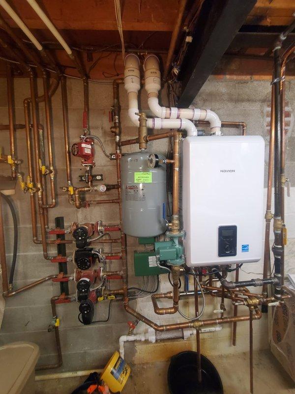 Inspected 2021 Navien combi boiler system reporting water leak. Verified leak location at copper pipe connection point near the main unit. Tightened braided stainless steel connection and checked all valves (red/blue handle shutoffs) for proper operation. System now functioning without leaks; recommended annual maintenance to prevent future issues.