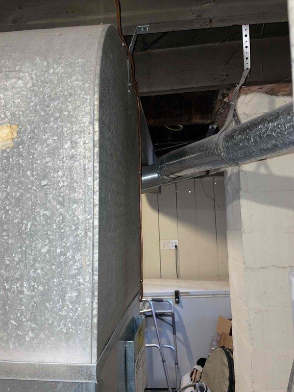 Conducted site assessment for replacement of 20-year-old basement furnace and installation of new central air conditioning system in single-family residence currently without AC. Evaluated existing ductwork, noting galvanized metal ducts with visible connecting joints and some rust at wall penetrations. Inspection revealed exposed structural elements requiring consideration during installation planning.