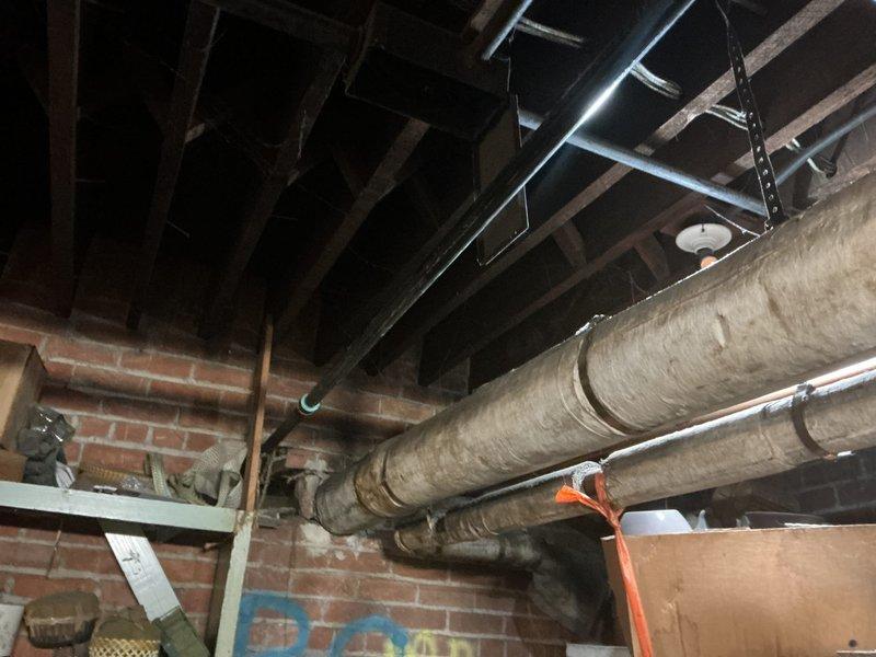 Completed gas line repair in basement utility area. Inspected and addressed issues with aged insulation on exposed gas pipes running through ceiling joists. Documented pre- and post-repair conditions with photographs showing the repaired gas line system and supporting metal brackets.