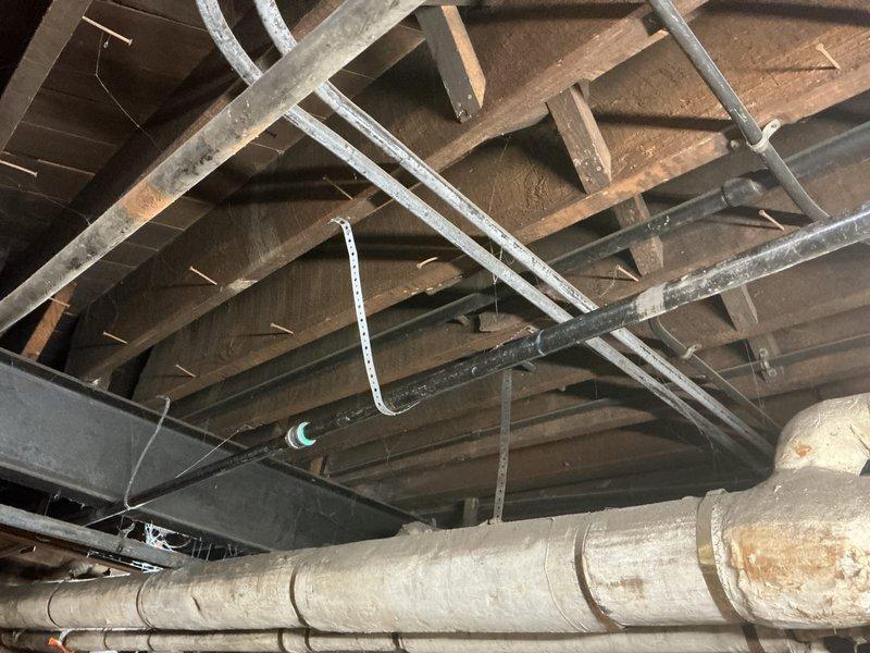 Completed gas line repair in basement utility area. Inspected and addressed issues with aged insulation on exposed gas pipes running through ceiling joists. Documented pre- and post-repair conditions with photographs showing the repaired gas line system and supporting metal brackets.