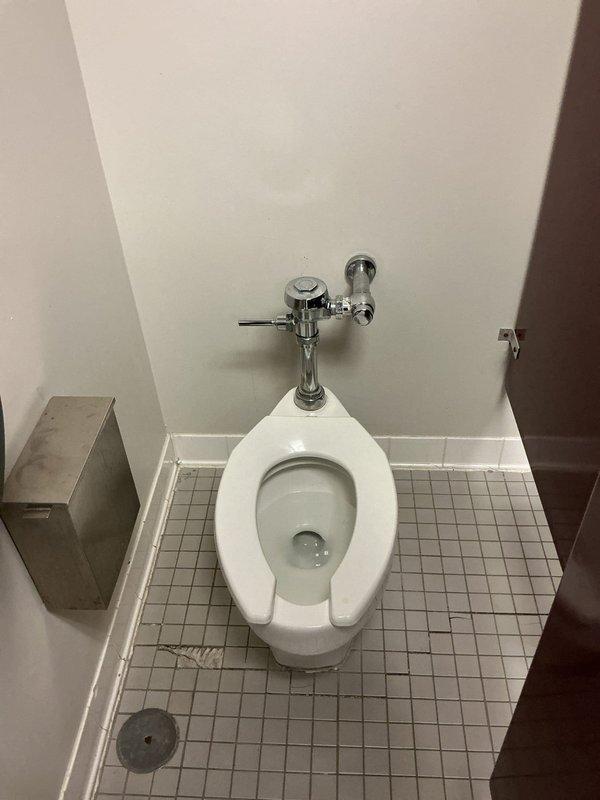 Replaced commercial toilet in restroom facility. Observed significant corrosion and mineral buildup around nearby floor drain requiring documentation. Completed installation of new fixture with proper connection to existing wall-mounted flush valve system.