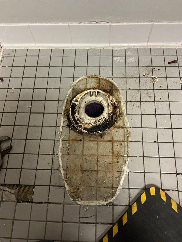 Replaced commercial toilet in restroom facility. Observed significant corrosion and mineral buildup around nearby floor drain requiring documentation. Completed installation of new fixture with proper connection to existing wall-mounted flush valve system.