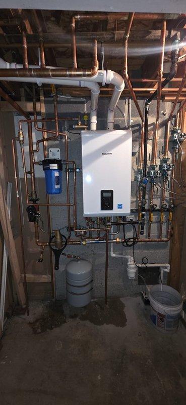 Completed installation of Navien boiler system with comprehensive copper pipe network in mechanical room. Identified factory defect in the Pentair water filtration unit for domestic hot water side showing cracking at threads and leakage. Replacement Peak Flow S filter has been ordered and will require follow-up visit for proper installation.