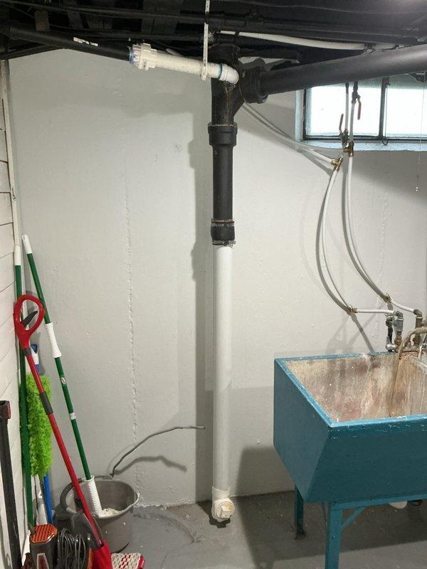 Responded to water leak call at rental property. Inspected basement utility area where black cast iron kitchen drain pipe was leaking at connection point to PVC pipe. Repaired the compromised joint between the cast iron and PVC sections, ensuring proper sealing and drainage function of the vertical waste line system.