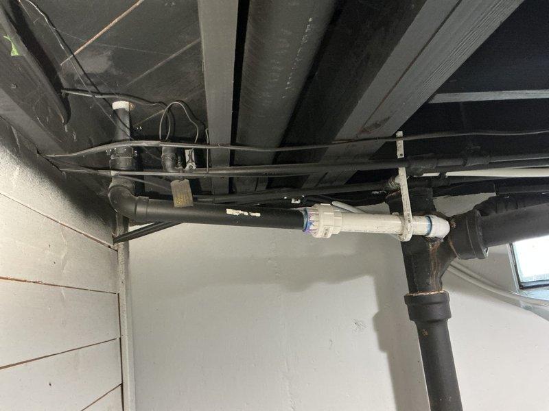 Responded to water leak call at rental property. Inspected basement utility area where black cast iron kitchen drain pipe was leaking at connection point to PVC pipe. Repaired the compromised joint between the cast iron and PVC sections, ensuring proper sealing and drainage function of the vertical waste line system.