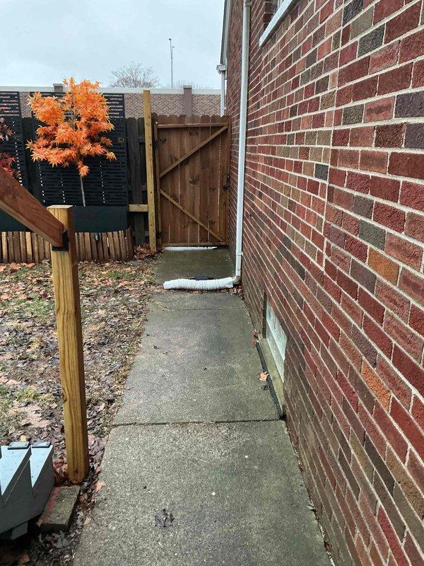 Conducted AC replacement estimate at residential property with limited access via narrow concrete walkway along brick exterior. Inspected existing HVAC system located in utility space, noting current installation configuration including PVC drainage, copper refrigerant lines, and electrical connections. Photos documented both external access constraints and internal system components for accurate replacement planning.