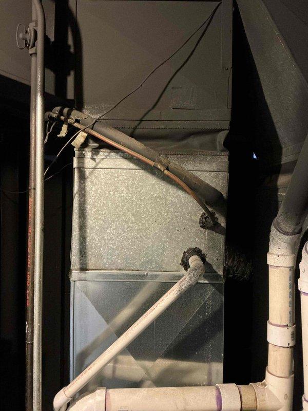 Conducted AC replacement estimate at residential property with limited access via narrow concrete walkway along brick exterior. Inspected existing HVAC system located in utility space, noting current installation configuration including PVC drainage, copper refrigerant lines, and electrical connections. Photos documented both external access constraints and internal system components for accurate replacement planning.