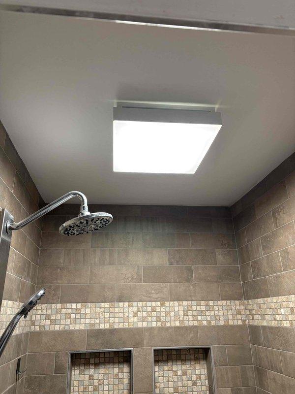 Installed new LED recessed light fixture in shower ceiling, ensuring proper waterproof sealing and electrical connections. Performed measurements of fixture placement and verified adequate clearance from shower head to comply with electrical code requirements for wet locations.