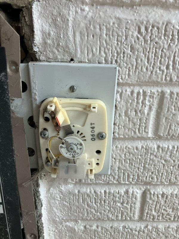 Performed diagnostic assessment on 30+ year old Suburban Manufacturing mini-split ductless heat pump located on customer's porch that was reported non-operational. Examination revealed severely outdated thermostat control system with mechanical components showing significant wear. Documented condition of internal wiring connections and temperature regulation mechanism for replacement recommendation.