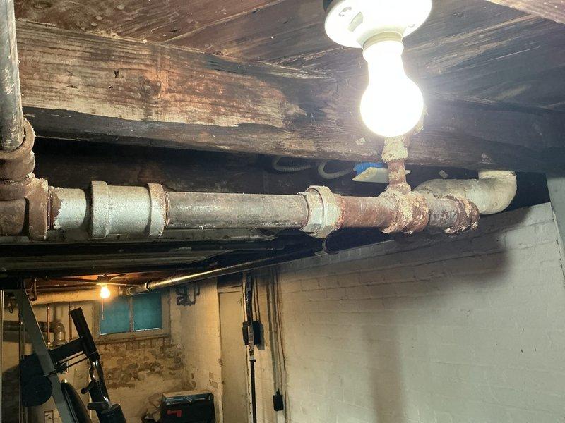 Responded to service call for steam pipe with holes in basement. Upon inspection, discovered significant corrosion and multiple perforations in the aging galvanized steam line running along ceiling joists. Replaced damaged section of pipe, ensuring proper connections and sealing to prevent future leaks.