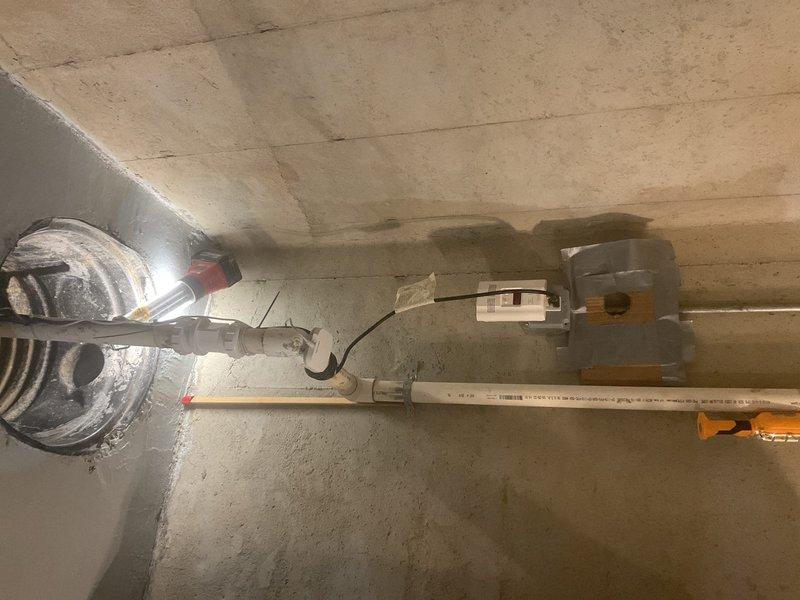 Replaced failing sump pump system in basement utility area, removing corroded metal components and installing new PVC discharge piping with proper electrical connections. System was thoroughly tested to ensure proper water evacuation and function of the new pump assembly.