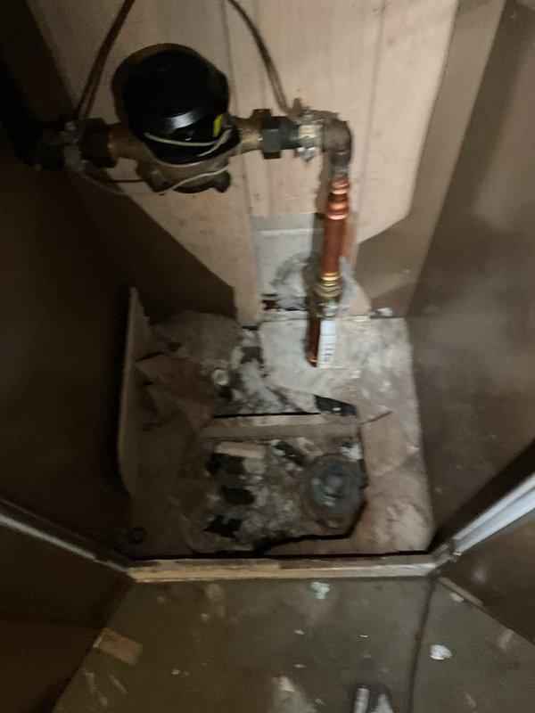 Responded to basement flooding incident in a 1960s home. Inspected the sump pump system and plumbing installation, noting water meter and copper pipe assembly with brass fittings. Identified and cleared drainage blockage affecting the sump pump discharge line, evidenced by the outdoor utility access point where water should properly exit.