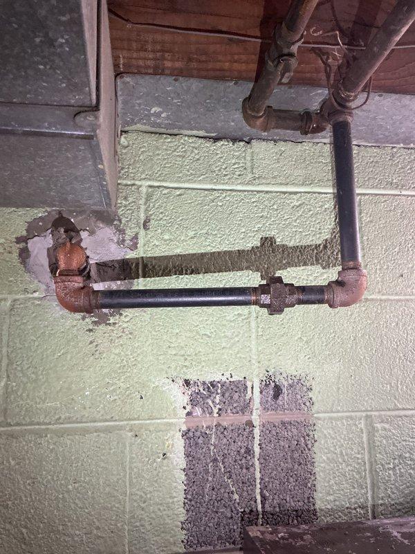 Responded to customer report of gas odor in basement. Performed comprehensive leak detection and identified gas leak at deteriorated copper fitting where black pipe connects to copper elbow joint on green cinder block wall. Completed pressure testing of gas line system, replaced damaged fitting, and verified system integrity with follow-up testing to ensure complete resolution of the leak.