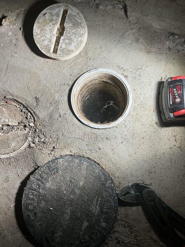 Inspected sump pump system in basement furnace room due to an ongoing driveway drainage issue. Examined multiple access points in concrete floor, including main sump pit and auxiliary drain openings. Documented condition of existing drainage system components with photographs for future reference.