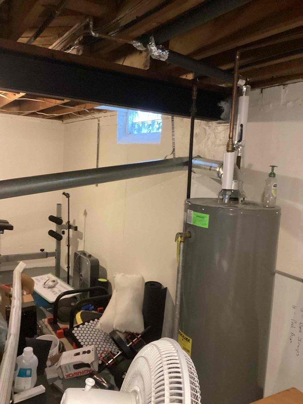 Completed inspection of aging HVAC system including a 2003 furnace and 1997 AC unit located in the basement for city certification purposes. Visual assessment revealed an older furnace installation with connected ductwork, condensate drainage system, and associated mechanical components, all showing signs of extended service life. Water heater, humidifier, and thermostat were also inspected as part of the comprehensive evaluation for rental property certification.