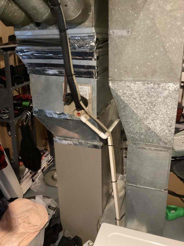 Completed inspection of aging HVAC system including a 2003 furnace and 1997 AC unit located in the basement for city certification purposes. Visual assessment revealed an older furnace installation with connected ductwork, condensate drainage system, and associated mechanical components, all showing signs of extended service life. Water heater, humidifier, and thermostat were also inspected as part of the comprehensive evaluation for rental property certification.