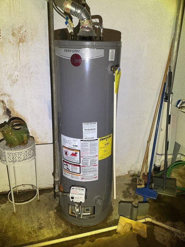 Diagnosed and serviced Performance brand water heater with thermopile voltage issues causing interrupted hot water supply throughout residence. Inspected unit in basement, noting significant water damage and staining on adjacent wall indicating possible previous leaks. Replaced defective thermopile component to restore proper functionality and ensure consistent hot water delivery.