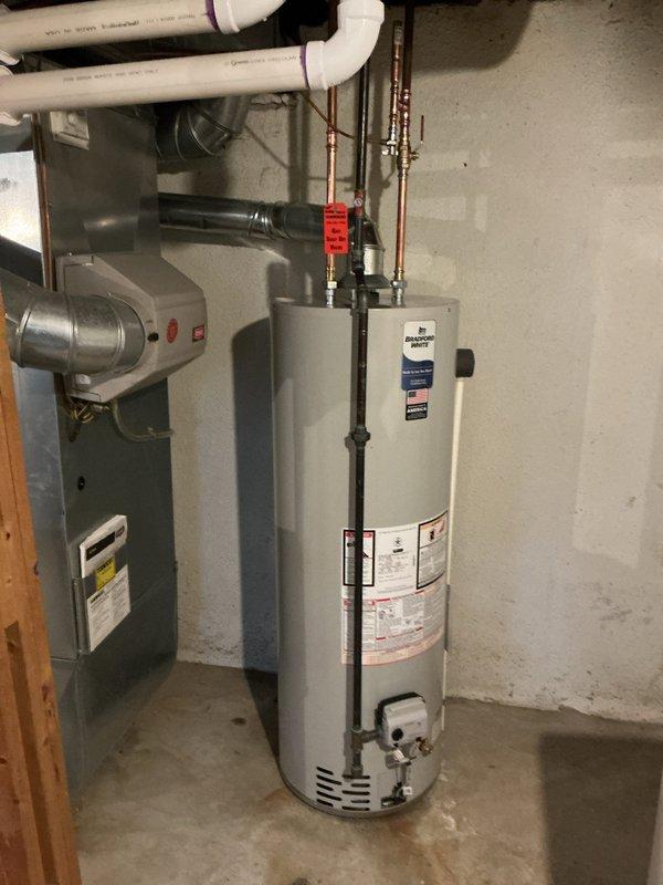 Successfully reconnected tanked water heater in utility room with proper copper and PVC piping connections. Installed necessary valves and pressure gauge at corner junction, ensuring proper function of the system alongside existing HVAC equipment.