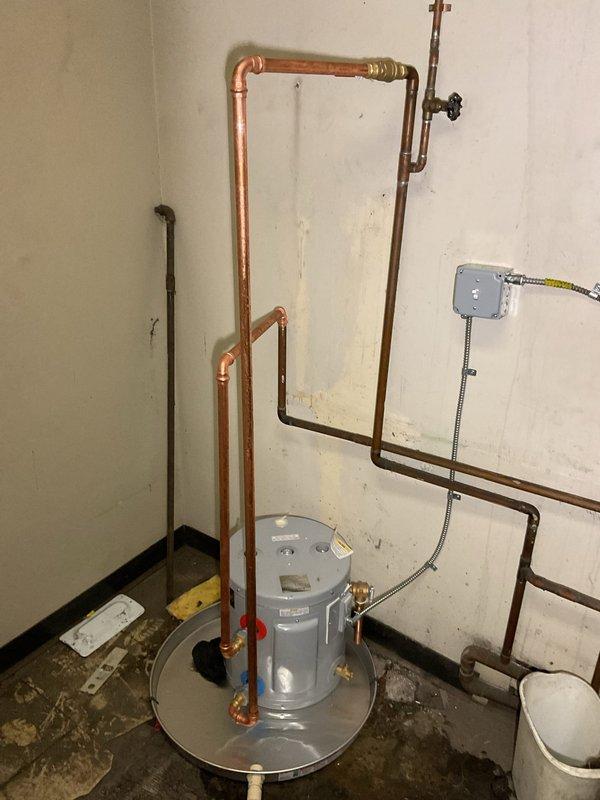 Successfully reconnected commercial tanked water heater in utility area, including installation of proper copper piping configuration with appropriate fittings. Verified electrical connections at junction box with toggle switch and ensured system was operational with all connections secure.