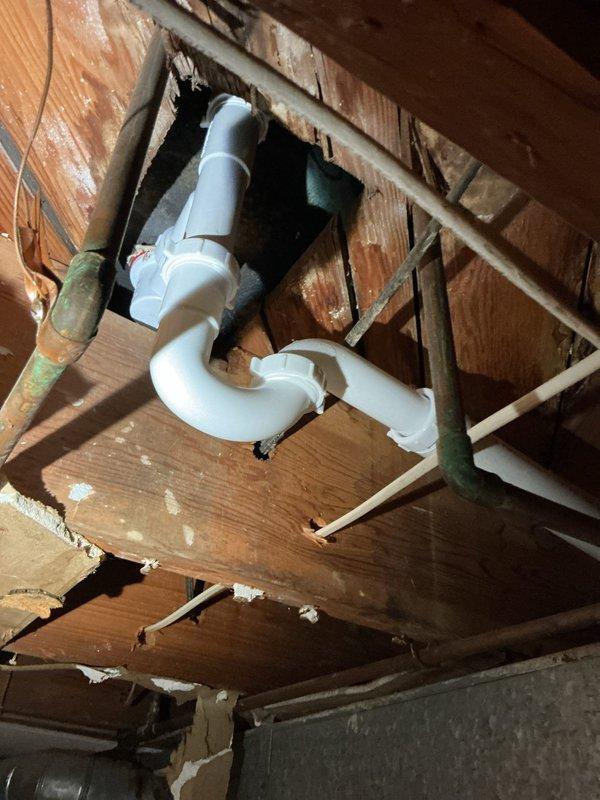 Replaced deteriorated drain assembly with new PVC components, installing proper S-trap configuration through floor joists and connecting to existing drain line. Installed new P-trap under kitchen sink with appropriate connections to sink drain flange, ensuring proper drainage and eliminating previous water staining issues.