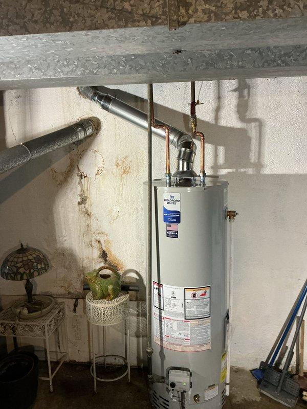 Successfully installed a new 40-gallon water heater in basement utility area with proper venting system and copper pipe connections. Removed old unit and completed all mechanical reconnections of hot water lines according to code requirements. System is now operational with no leaks observed at connection points.