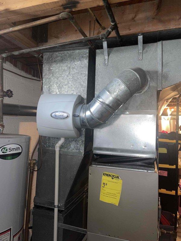 Performed evaluation of 15-year-old residential AC system. Current unit is operational but approaching end of service life. Inspection revealed EnergyAir furnace system with connected AprilAire humidifier and A.O. Smith water heater in basement location, with coil placement also in basement. Roof inspection showed well-maintained chimney venting system. Provided replacement options for aging AC system with natural gas heating configuration.