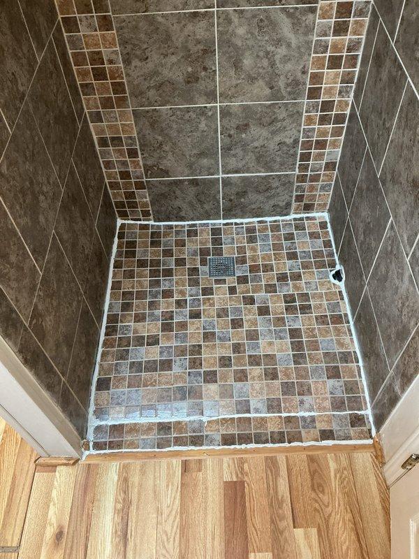 Responded to a service call for water seepage from under a walk-in shower. Inspection revealed inadequate waterproofing at the shower threshold where tile meets wooden flooring. Further investigation of the crawl space showed moisture penetration and deteriorating insulation beneath the shower area, confirming the leak source.