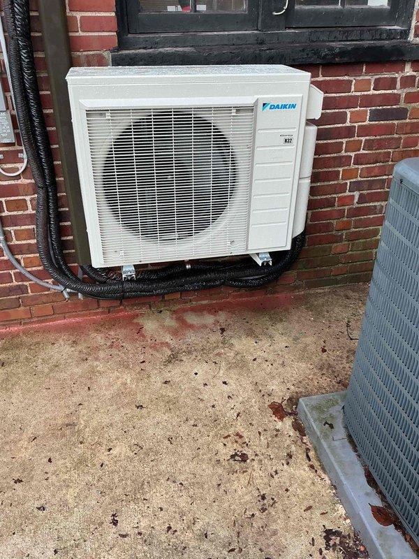 Responded to callback for Daikin mini-split system showing "High Discharge Pipe Control" error message. Inspected outdoor unit mounted on brick wall with proper insulated refrigerant lines and electrical connections. System was diagnosed, error cleared, and unit returned to normal operation with verification of proper discharge temperatures.