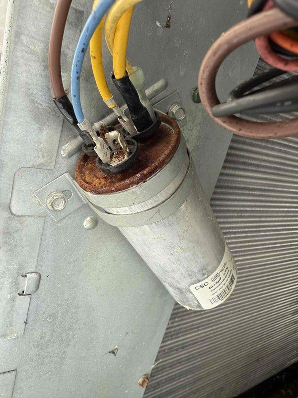 Performed comprehensive tune-up on outdoor HVAC system, including inspection of blower motor assembly, electrical connections, and capacitor. Noted significant rust and corrosion on capacitor terminals requiring monitoring for future replacement. Cleaned accumulated dust and debris from interior components and verified proper operation of humidifier, thermostat, and hot water tank as part of maintenance service.
