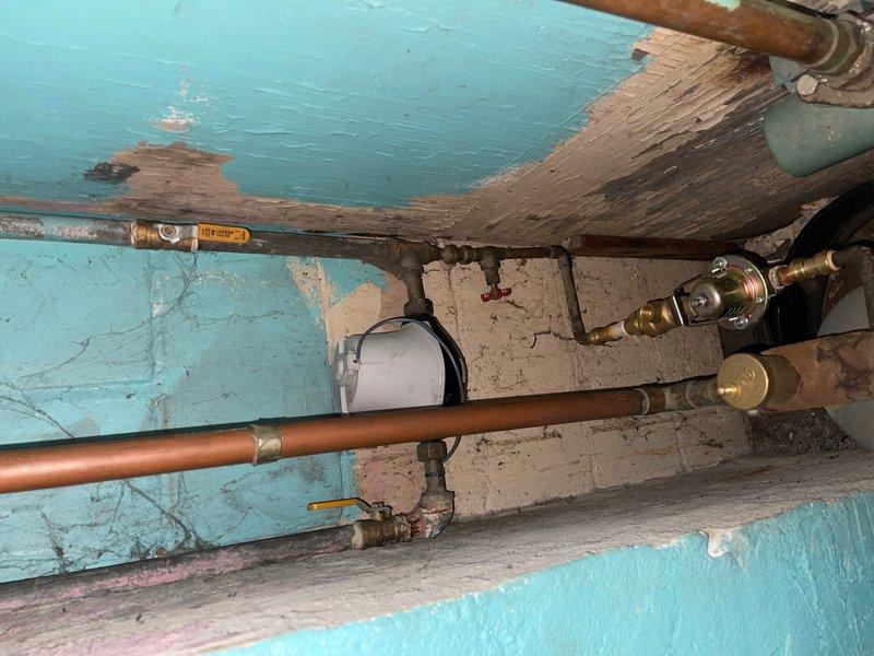 Installed a ground strap on the water meter to establish proper electrical grounding. Existing plumbing system consisted of copper pipes with various brass fittings showing normal patina consistent with age. Completed installation ensures electrical safety compliance for the household water system.