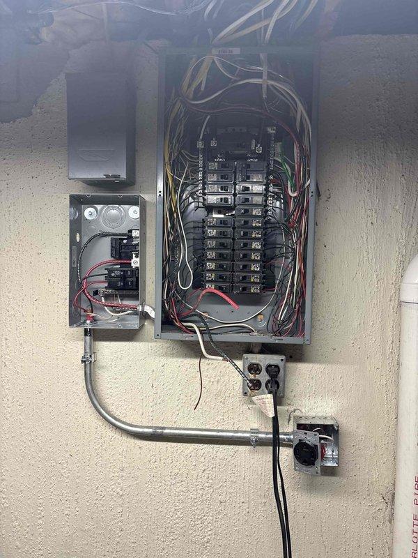 Completed installation of a surface-mounted duplex receptacle on wooden trim, along with a comprehensive electrical panel upgrade. Successfully installed and wired the main breaker panel with proper circuit distribution, including secondary sub-panel integration and conduit routing to connected outlets.