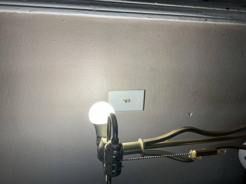 Completed whole home electrical inspection, examining various lighting fixtures and outlets. Verified proper operation of desk lamp with adjustable brass arm and functioning wall outlet. Inspected ceiling-mounted dome light fixture with frosted glass cover and metal trim, confirming secure installation and operational status.