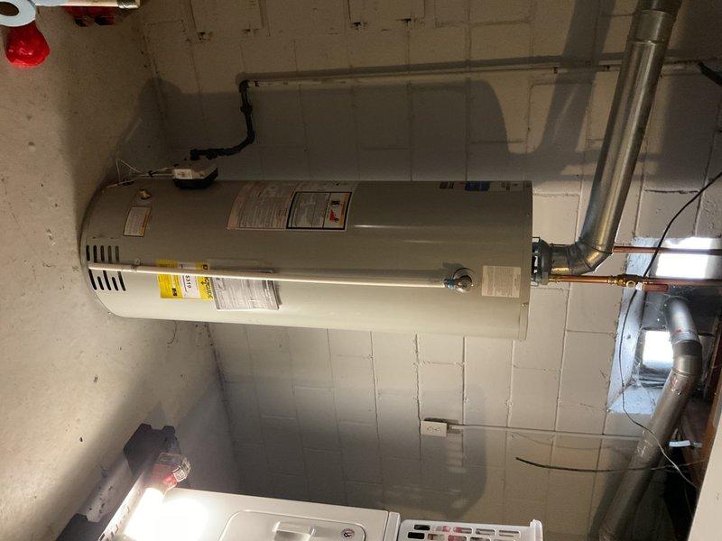 Successfully installed a 40-gallon tanked water heater with proper hot and cold water connections using PEX piping with copper fittings. Completed mechanical reconnection of the unit, including proper venting and secure mounting against the concrete block wall in the utility area.