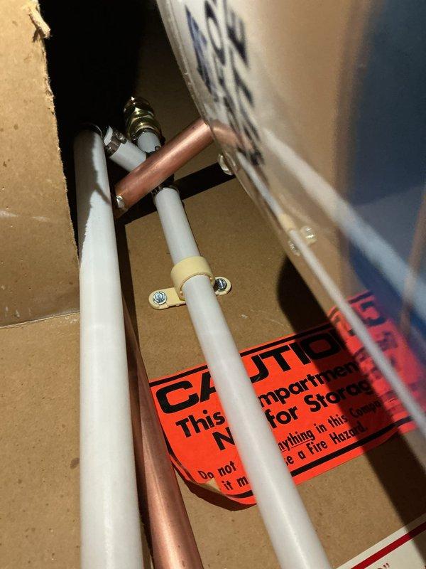 Successfully installed and reconnected a new tanked water heater in residential utility closet with proper copper pipe connections and mounting hardware. Verified all plumbing connections were secure and leak-free. System is now operational with appropriate warning labels in place regarding fire hazards and compartment usage.