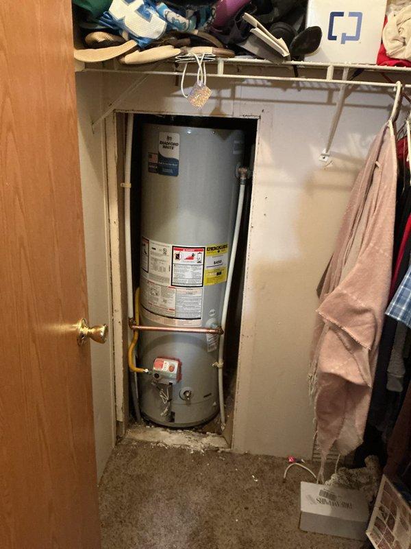 Successfully installed and reconnected a new tanked water heater in residential utility closet with proper copper pipe connections and mounting hardware. Verified all plumbing connections were secure and leak-free. System is now operational with appropriate warning labels in place regarding fire hazards and compartment usage.