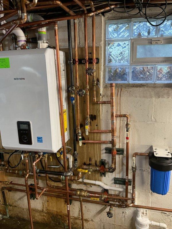 Conducted follow-up inspection on Navien boiler system after previous repairs due to customer's report of inefficient heating. Examined complete hydronic system including circulation pumps, expansion tank, and copper supply/return lines. System appears professionally installed with proper valves and gauges in place. No visible issues identified with the equipment or installation that would cause heating inefficiency.