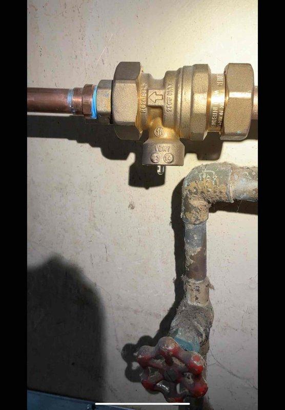 Diagnosed water leak originating from 12-year-old boiler located in kitchen. Identified heavily corroded pipe section with significant mineral deposits as the source of leakage. Replaced deteriorated section with new brass backflow preventer valve and copper pipe connections, ensuring proper seals at junction points to prevent future leakage.