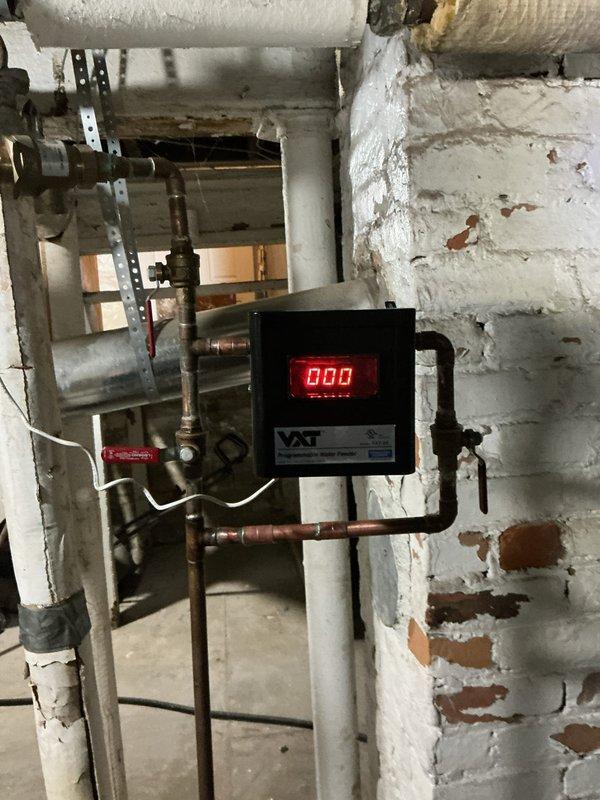 Responded to service call for non-functioning boiler with overfilled sight glass and leaking regulator valve. Diagnosed severe corrosion at copper pipe T-junction causing system failure. Replaced faulty VXT-24 Auto Feeder and repaired corroded piping connection to restore proper boiler operation and water level regulation.