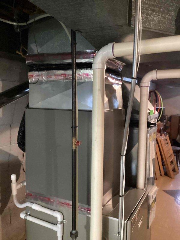 Conducted diagnostic assessment on Bryant Plus 90i furnace exhibiting temperature inconsistency and noise issues. Identified failed control board and signs of secondary heat exchanger deterioration in the approximately 10-year-old unit located in basement. Documented existing installation measurements and exhaust ventilation configuration for replacement recommendation.