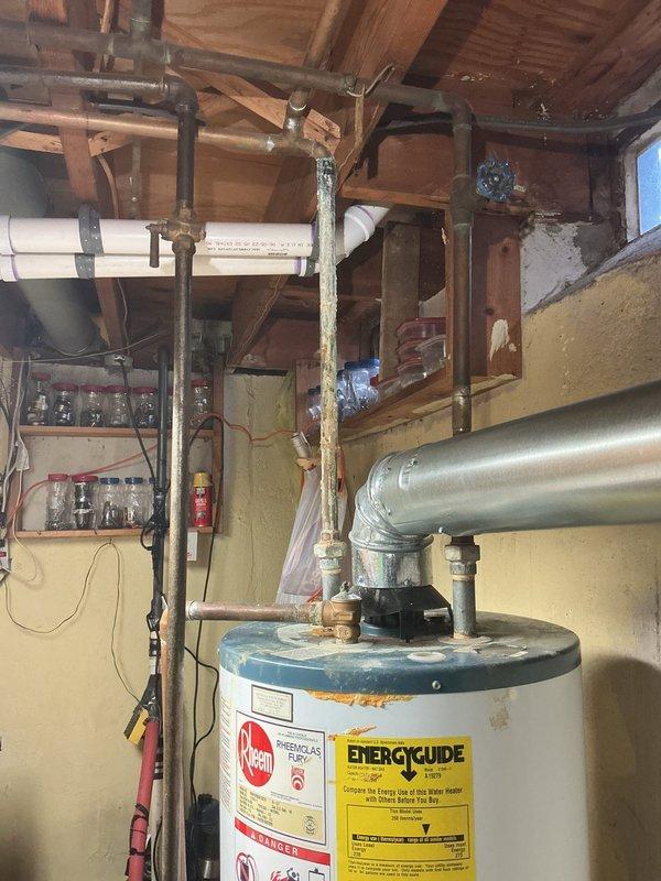 Successfully installed a 40-gallon Rheem tanked water heater in basement utility area with all required copper piping connections and proper venting. Installation included a drip pan with alarm system for leak protection as specified. All connections were tested and system is functioning properly.