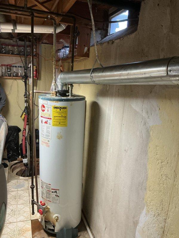 Successfully installed a 40-gallon Rheem tanked water heater in basement utility area with all required copper piping connections and proper venting. Installation included a drip pan with alarm system for leak protection as specified. All connections were tested and system is functioning properly.