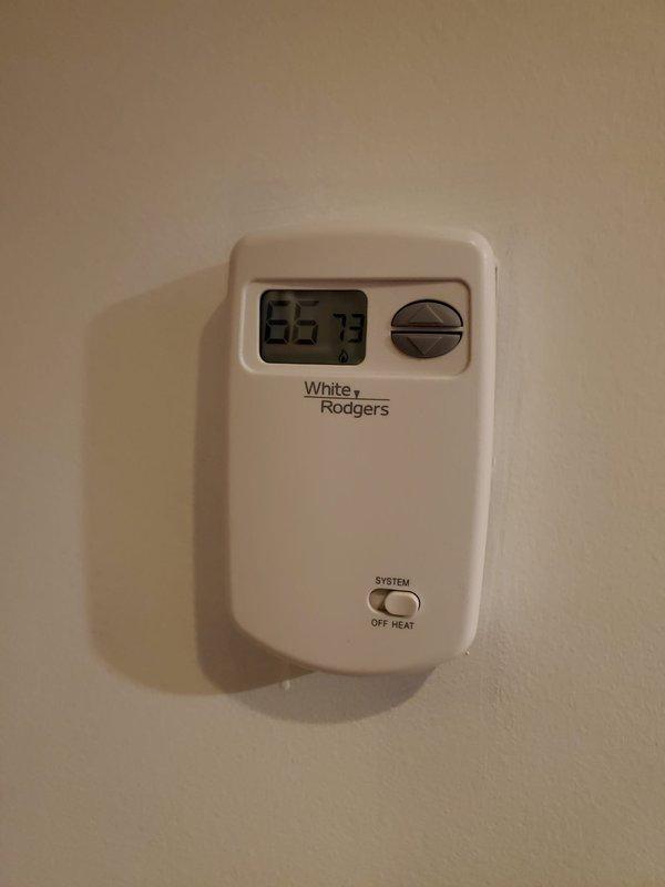 Performed maintenance tune-up on 7-year-old Cozy wall furnace located in basement. Inspected system components, cleaned ventilation grilles, and verified proper thermostat operation (White-Rodgers unit displaying 56.73°F). Unit successfully restored to operational status after service.