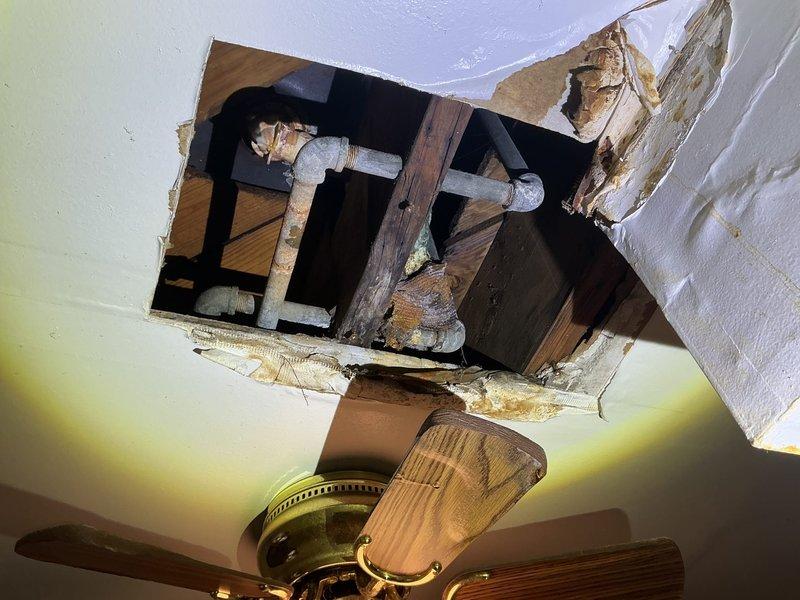 Conducted inspection of water leak originating from shower/bath fixture that was causing damage to kitchen ceiling below. Documented significant ceiling damage with visible corrosion on exposed pipes and water staining. Provided estimate for complete replacement of bathroom fixtures including showerhead, faucet, and spout to resolve the ongoing leak issue.