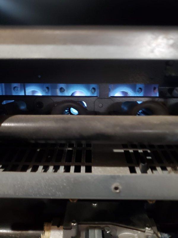 Performed Gold Furnace Inspection on a 10-year-old residential unit located in basement. Visual inspection confirmed proper thermostat operation (Emerson model showing 73° current/67° set point) and examined heat exchanger components with blue flame indication suggesting proper combustion. System was operational with no immediate concerns identified.