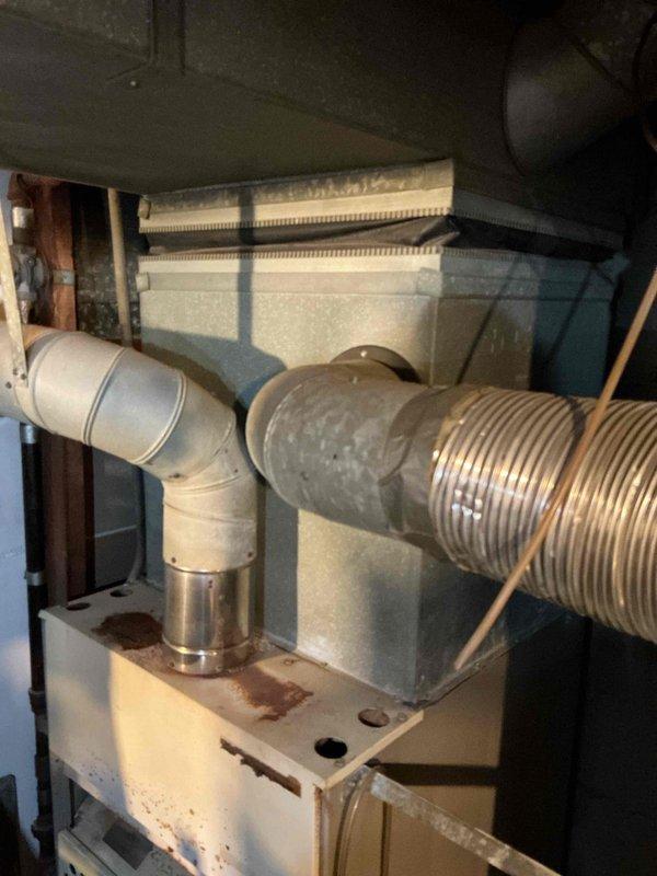 Performed inspection of non-functioning furnace system in customer's home. Observed aged furnace unit with visible rust and discoloration, currently shut off. System includes wall-mounted thermostat reading 56 degrees, rectangular plenum, and round metal ductwork with PVC venting. Provided replacement estimate for natural gas furnace installation.
