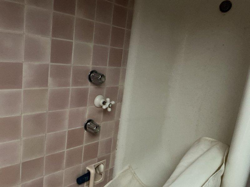 Conducted follow-up site visit to re-evaluate previous estimate. Inspected bathroom fixtures including bathtub/shower enclosure with damaged tile surround and aging water control handles. Also examined basement utility area with deteriorated pipe insulation, visible corrosion on metal components, and signs of moisture damage on concrete wall surfaces. Documented conditions with photographs for revised quote preparation.