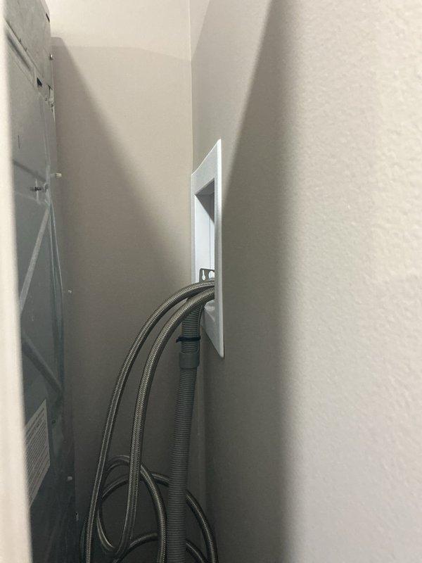 Conducted inspection of plumbing code violations in two bathrooms. Identified improper utility box installation with exposed braided supply line and drainage hose in a narrow wall cavity. Also found copper supply lines with multiple fittings and red valve handles mounted to wooden support beams, requiring proper securing and code-compliant installation.