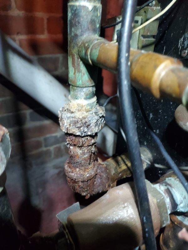Responded to service call for a water boiler exhibiting vibration issues in residential basement. Inspection revealed severe corrosion and deterioration on multiple copper pipe junctions and valves, particularly at the pressure regulator mounted on the expansion tank. Replaced corroded components, secured loose fittings, and performed system test to confirm proper operation with no further vibration.